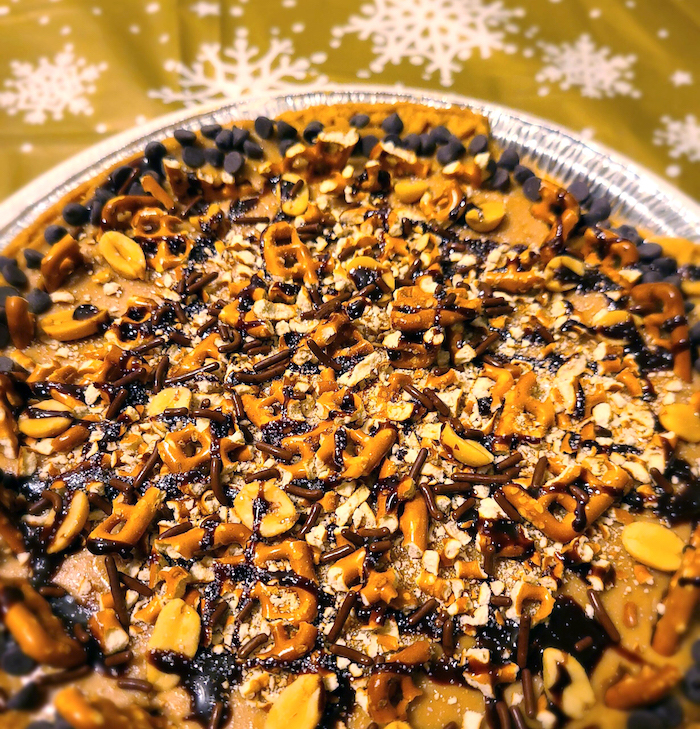 vegan chocolate peanut butter pretzel pie on a white plate against a tablecloth with snowflakes