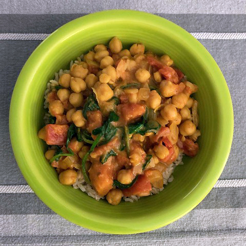 bird's eye view of vegan tikka masala in a grew bowl on a gray background.