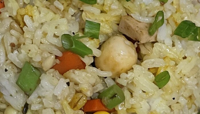 lotus seed fried rice garnished with chopped green onions on a plate.