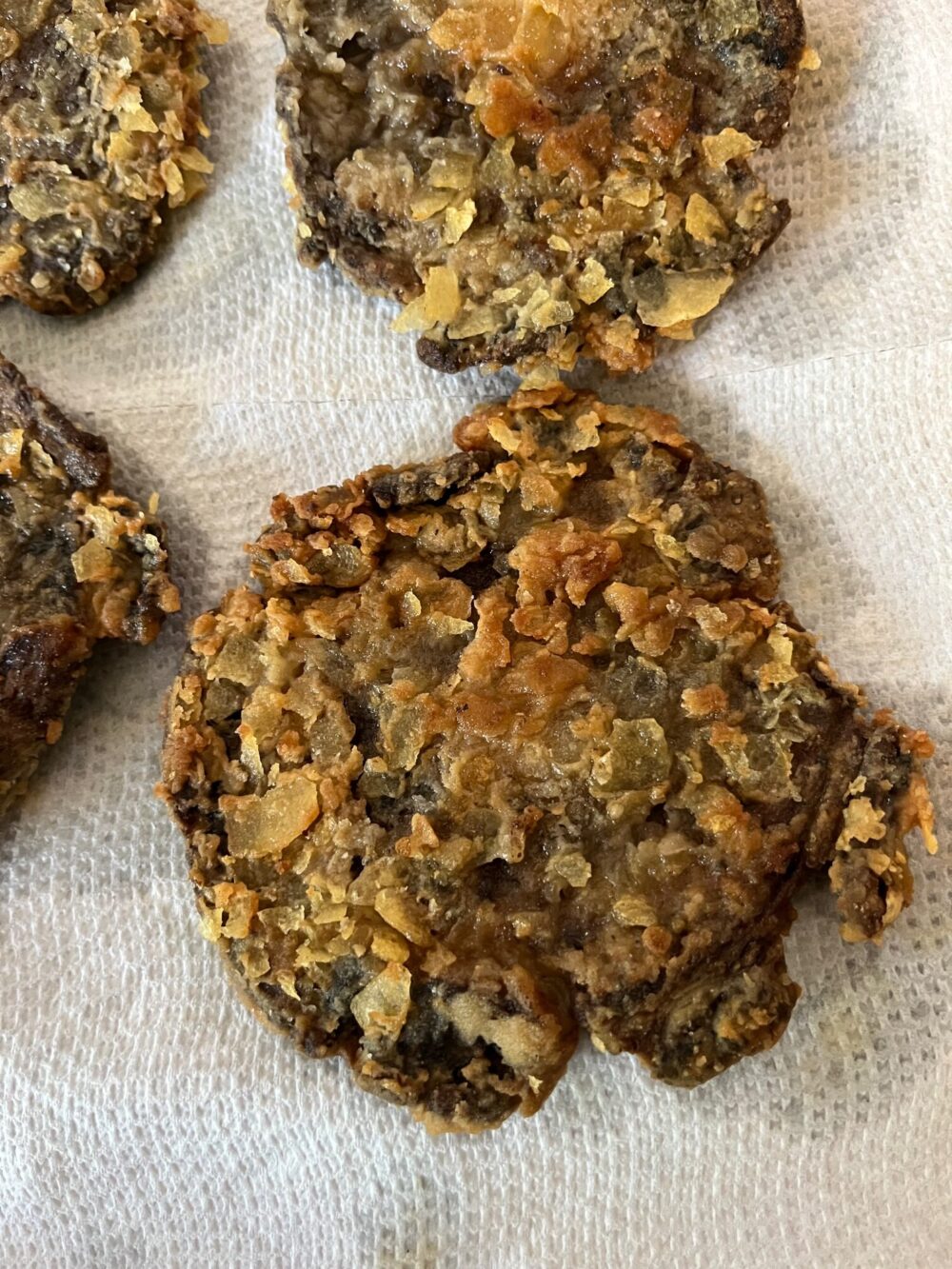 fried portobello caps drained of excess oil on paper towels.