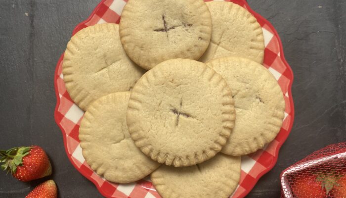 vegan strawberry-filled pillowy cookies on a red and white patterned plate.